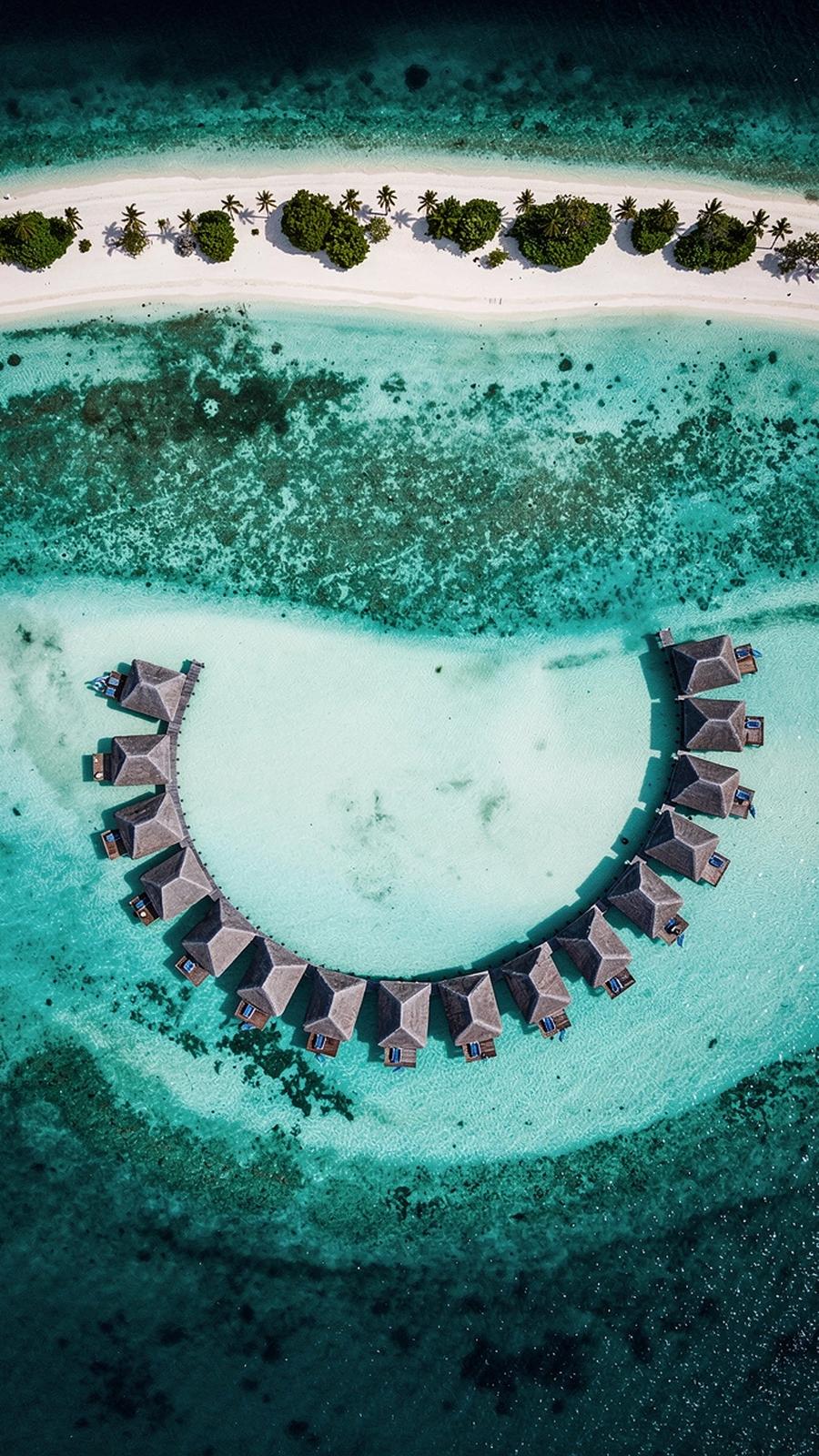 Aerial view of a Maldives atoll with overwater villas above a turquoise lagoon